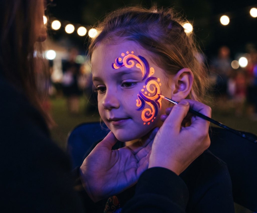 Neon face painting under black light at a Torrance community event